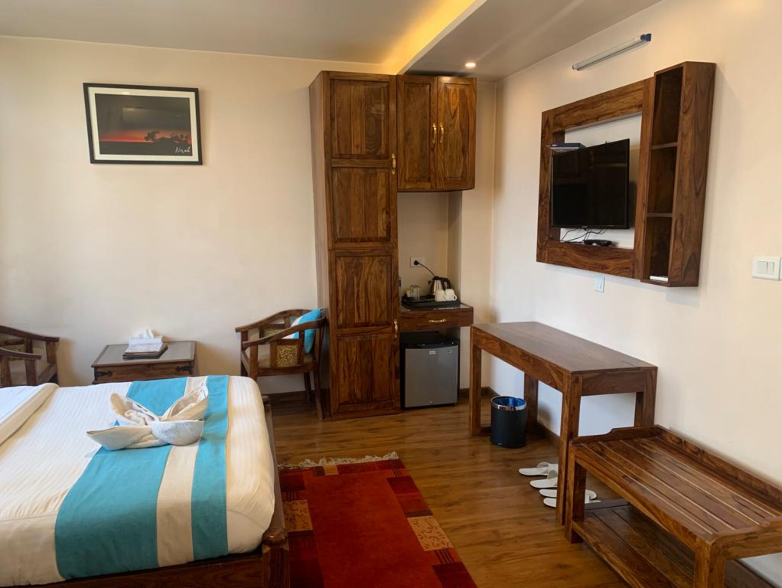 Una habitación de hotel con cama, escritorio, armario y televisión fijada en la pared.