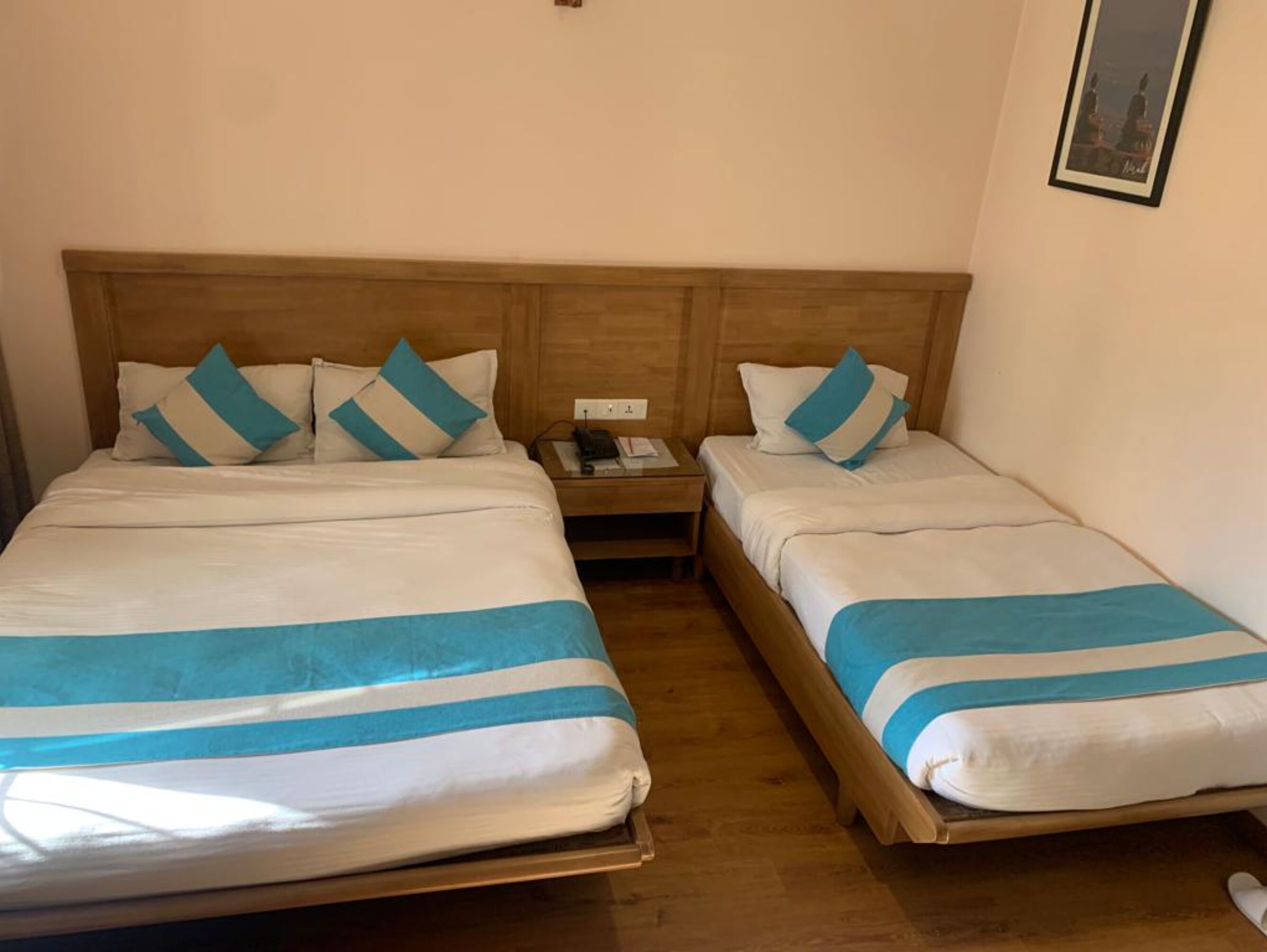 A double room with two beds, each with a wooden headboard, white bedding, and blue-striped blankets.