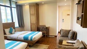 A hotel room with two beds, a sofa, a small table, and a chair. - Hotel Tapas (Kathmandu)