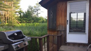Une cabane en bois avec un barbecue sur la véranda.