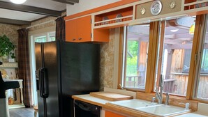 Une cuisine avec un réfrigérateur noir, des placards orange et un plan de travail en bois.