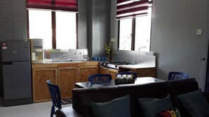 Un espace de vie compact comprenant un coin cuisine, un coin repas et un espace détente avec un canapé et des fauteuils.