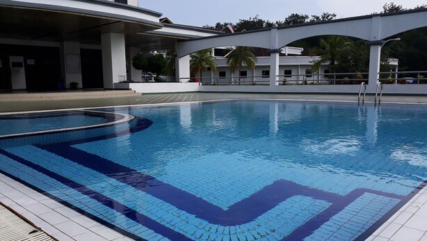 Une piscine dotée d’une terrasse carrelée et d’un espace couvert avec des escaliers.