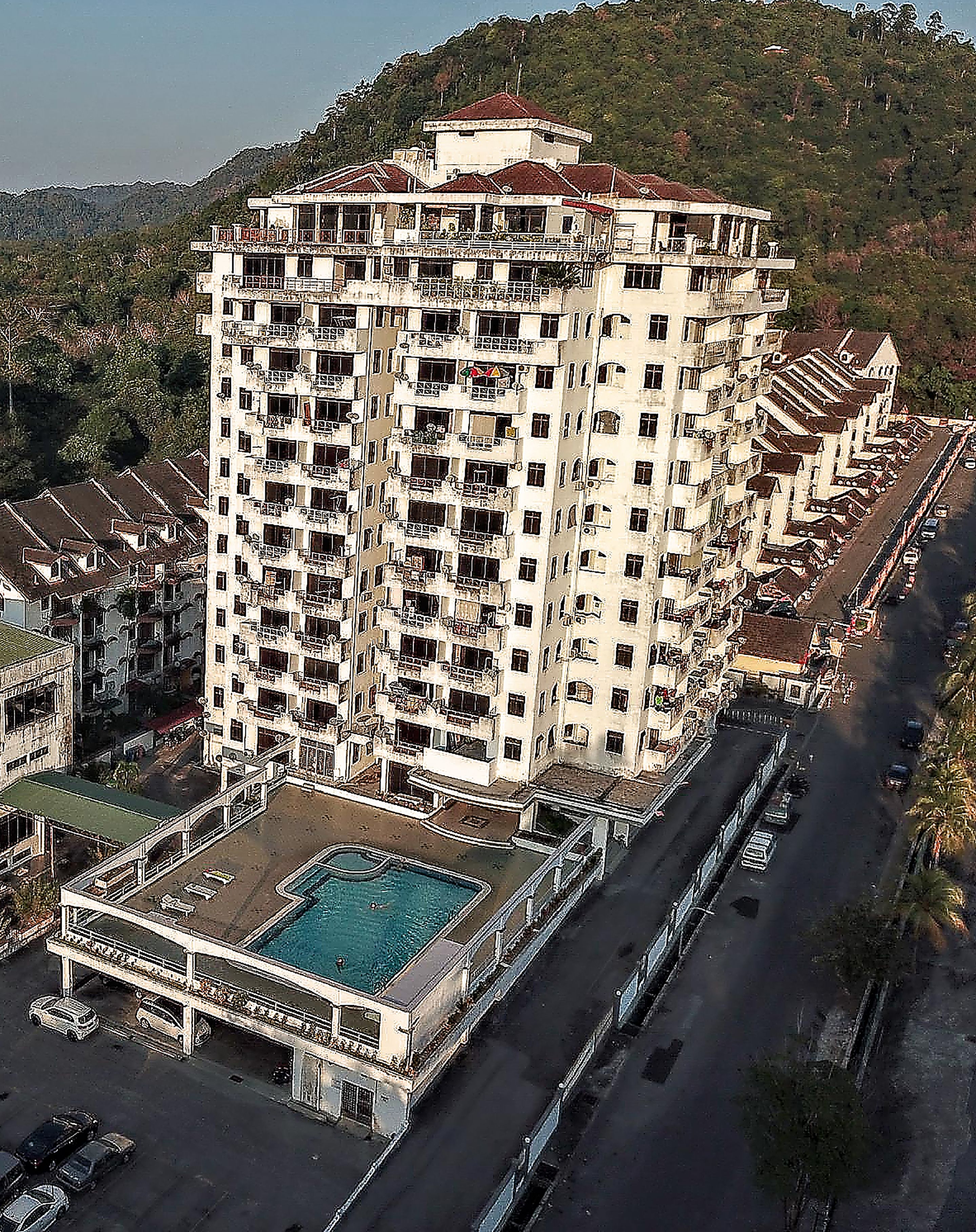 A multi-story hotel with a rooftop pool and a view of the surrounding area.