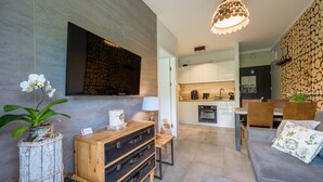 Una sala de estar moderna con un televisor de pantalla plana, un mueble de madera, un sofá y una zona de comedor con una mesa y sillas de madera.