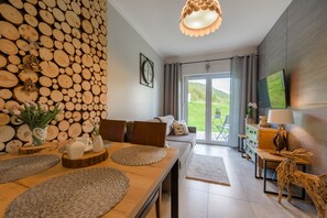 Un salon moderne avec un mur en bois brut, un coin repas doté d’une table en bois et un canapé.