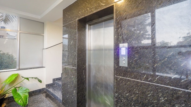 An elevator with a marble wall and a digital display showing the floor number. - Treebo Anjani Fortune Suites (Bengaluru)
