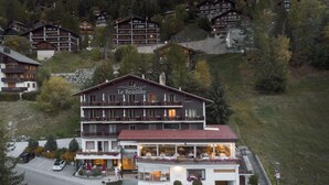 Ein mehrstöckiges Hotel mit Restaurant im Erdgeschoss, eingebettet in eine hügelige Landschaft.