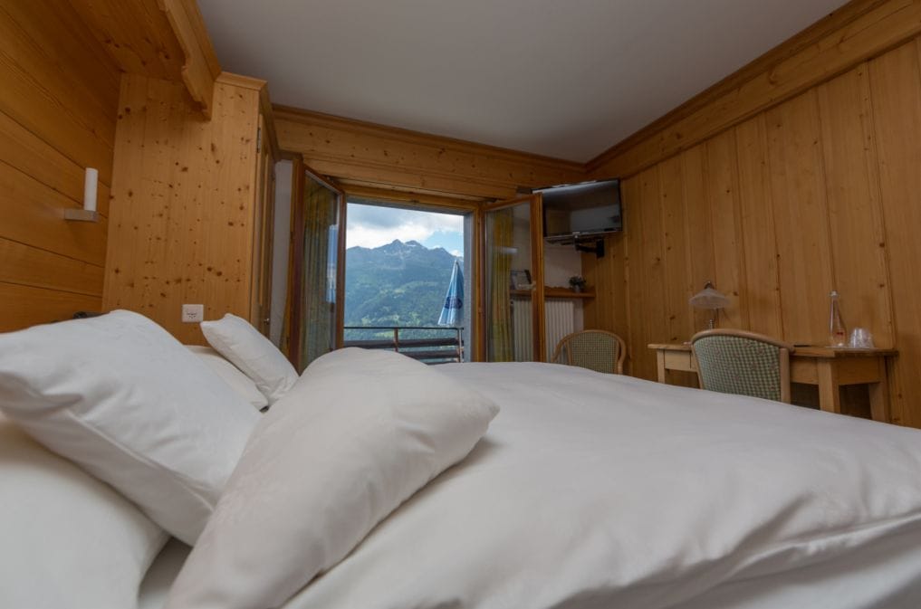 Una habitación de madera con una cama, un escritorio y un televisor.