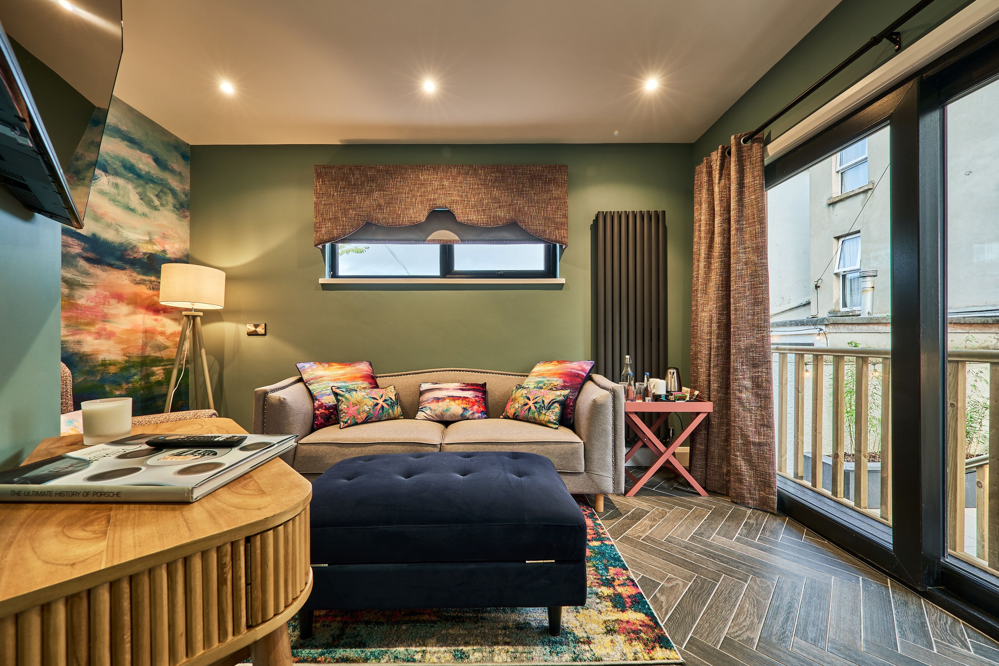 A modern living room with a sofa, ottoman, and a table with a book.