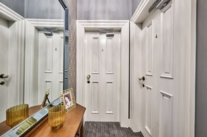 Un pasillo con puertas blancas, un banco de madera y un tapete estampado.