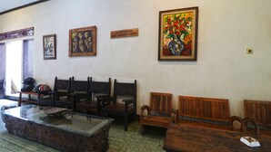 Un área de espera con bancos de madera, una mesa con cubierta de vidrio y varias obras de arte enmarcadas en la pared.