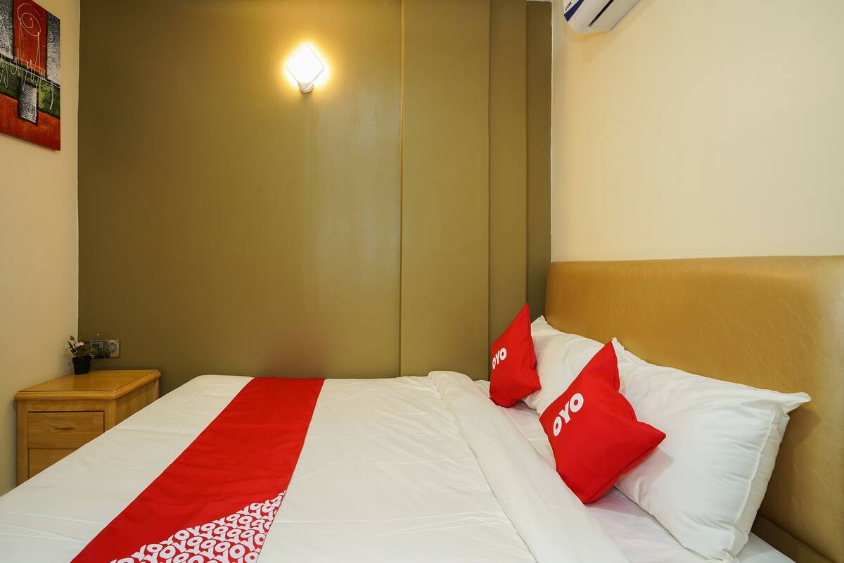 Une chambre d’hôtel comprenant un lit, une table de chevet, une lampe fixée au mur et une œuvre d’art décorative.
