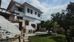 Ein zweistöckiges Haus mit einer Terrasse, einem Essbereich und einem kleinen Garten.