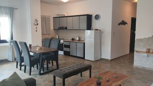 Eine moderne Küche mit Essbereich, ein Wohnbereich mit Sofa und Couchtisch sowie ein an der Wand befestigter Fernseher.