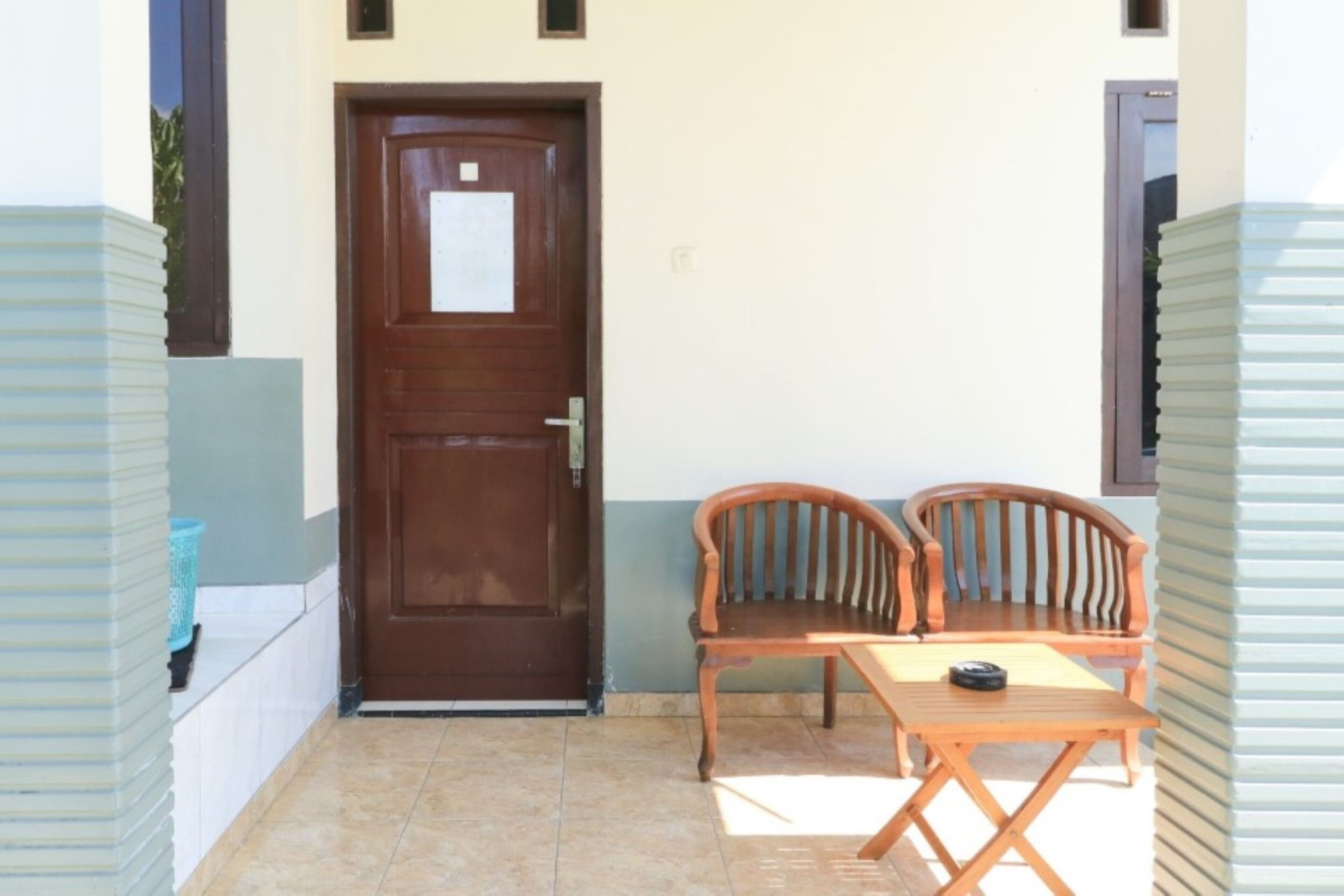 A small outdoor area with a wooden door, two wooden chairs, and a table.