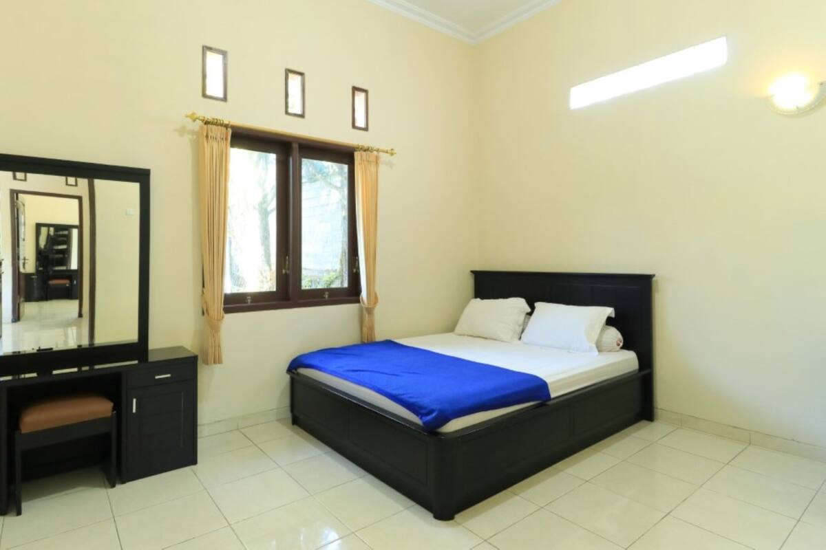 A bedroom with a bed, a desk, and a mirror.