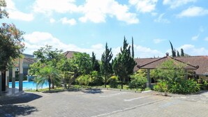 A courtyard with a paved area, a swimming pool, and buildings with tiled roofs. - Villa Bunga (Batu)
