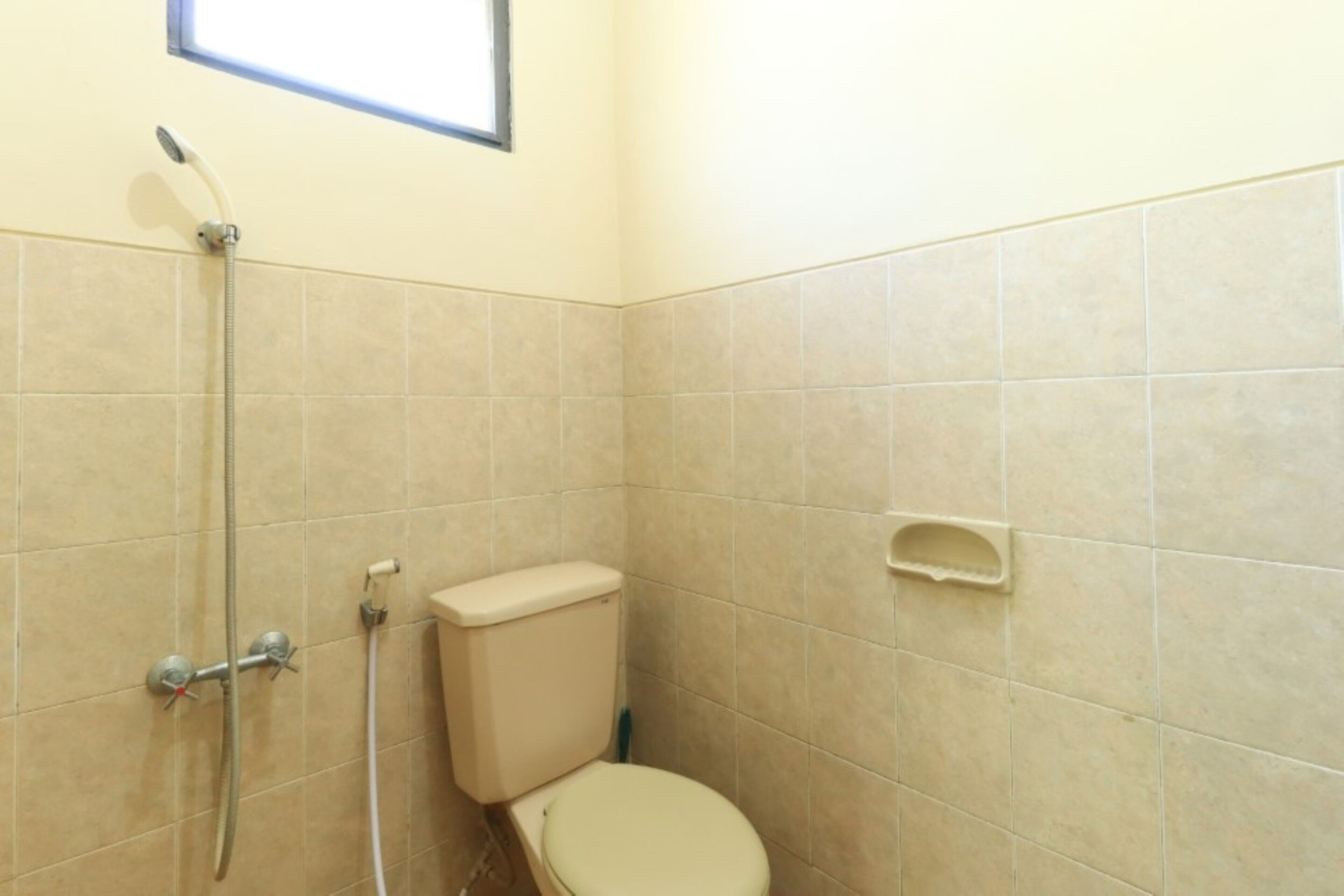 Ein kleines Badezimmer mit Toilette, Dusche und Fenster.