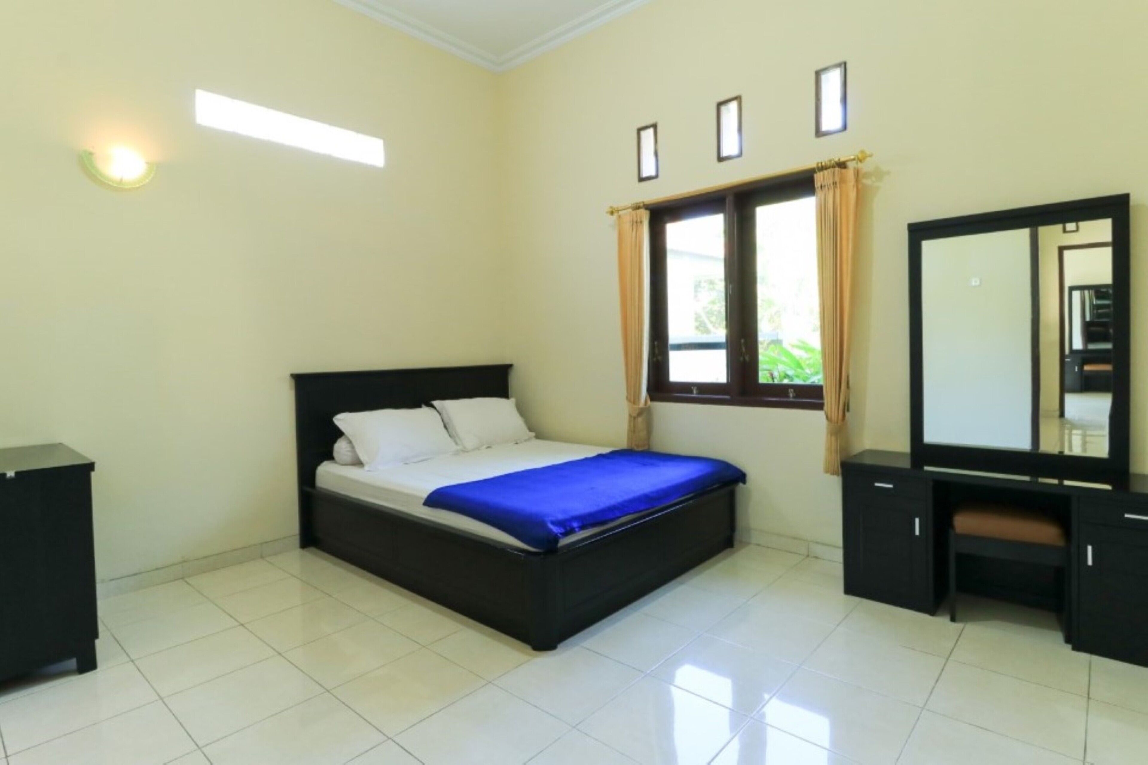 A bedroom with a bed, a desk, and a mirror.