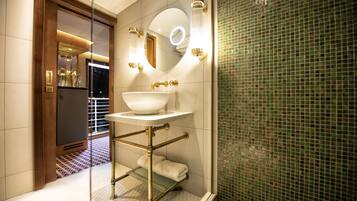 A modern bathroom with a large mirror, a white sink, and a glass shelf.