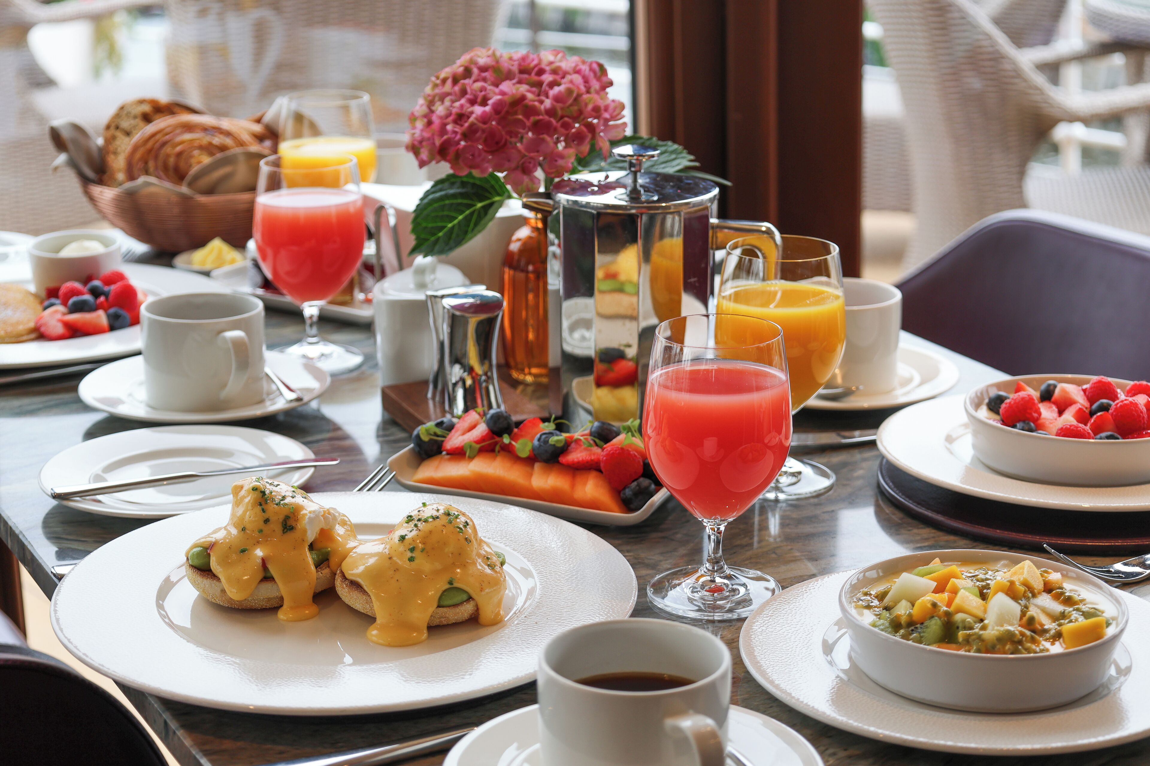 Una escena de desayuno con diversos platos, bebidas y un florero decorativo.