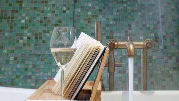 A bathroom with a green mosaic wall, a wooden tray with a glass of water, and a towel rack.