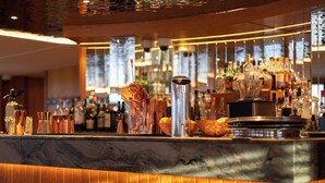 Zona de bar con encimera de mármol, copas y botellas diversas.