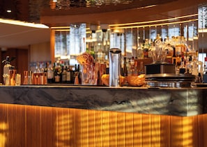 A bar area with a marble countertop, various glassware, and bottles.
