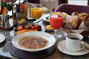 A breakfast setting with a bowl of cereal, a cup of coffee, and a glass of orange juice on a marble table.