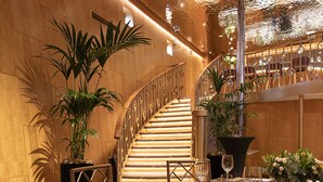 A dining area with a staircase, potted plants, and a table set for a meal. - Fingal - A Luxury Floating Hotel (Edinburgh)