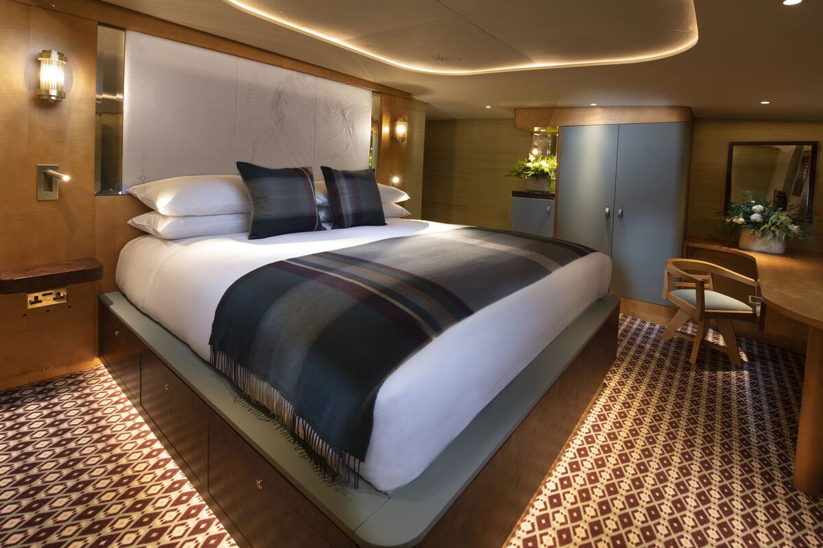 Quarto de hotel moderno com uma cama grande, uma escrivaninha e um espelho.