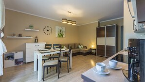 Ein modernes Wohnzimmer mit Essbereich, einer Couch, einer Kaffeemaschine und einem Bücherregal.