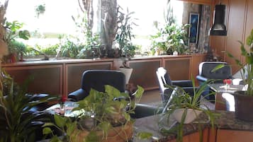 Una habitación con un ventanal grande, paneles de madera y varias plantas en macetas.