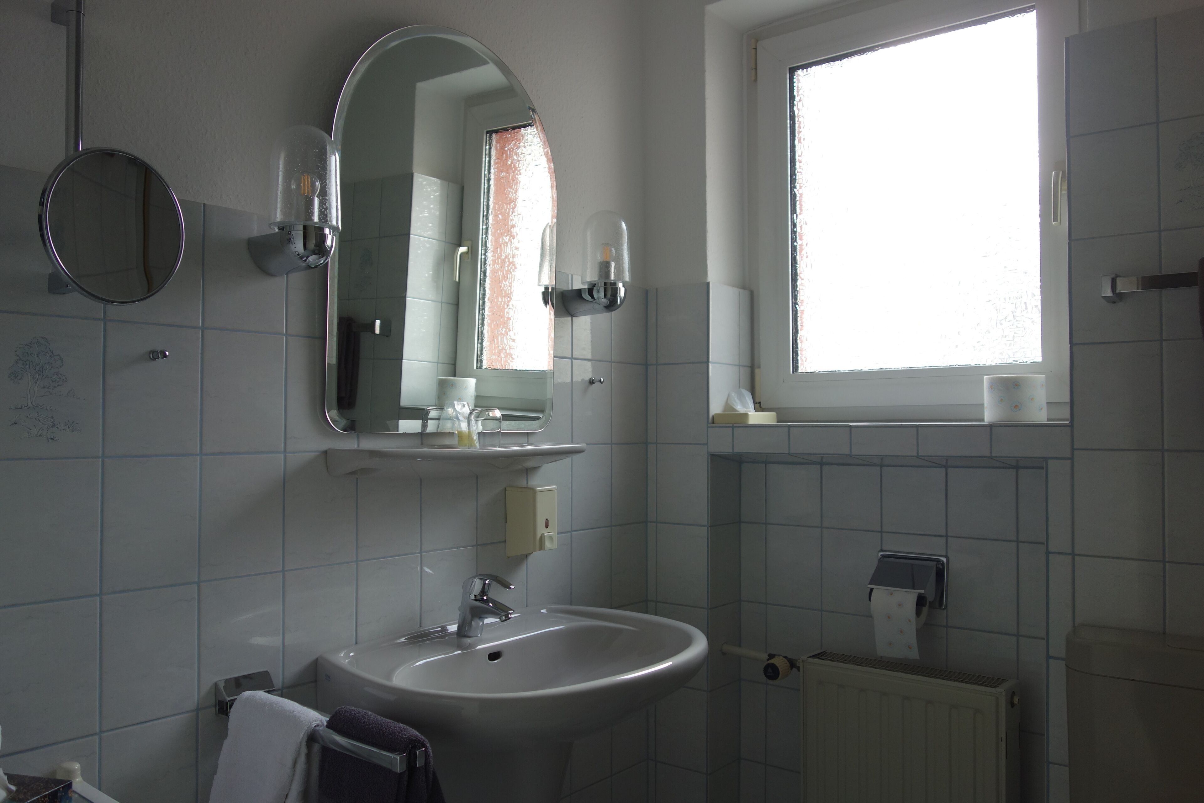 A bathroom with a sink, mirror, and window.
