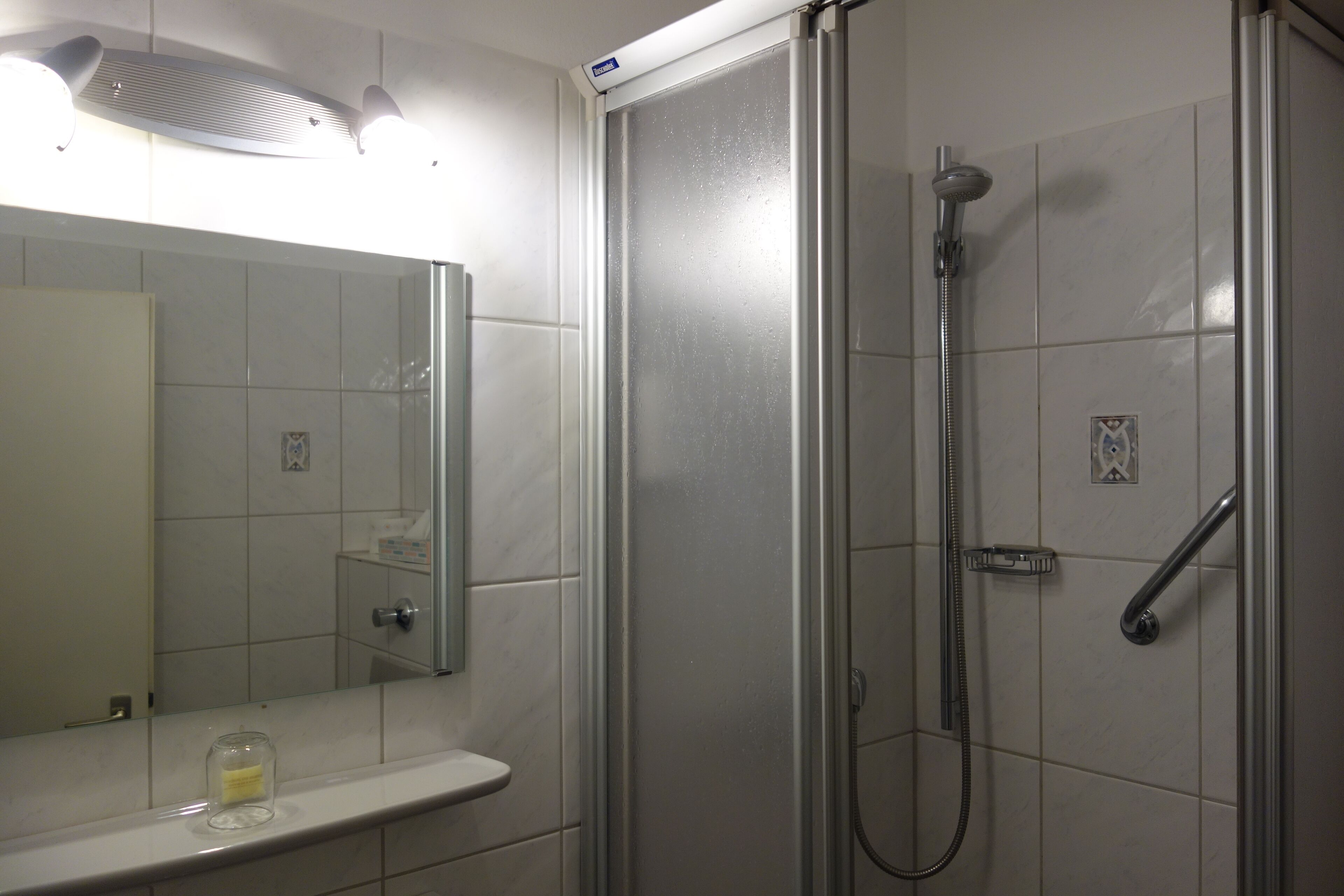 A bathroom with a shower, a sink, and a mirror.