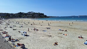 Une plage où des gens se prélassent au soleil et se baignent.