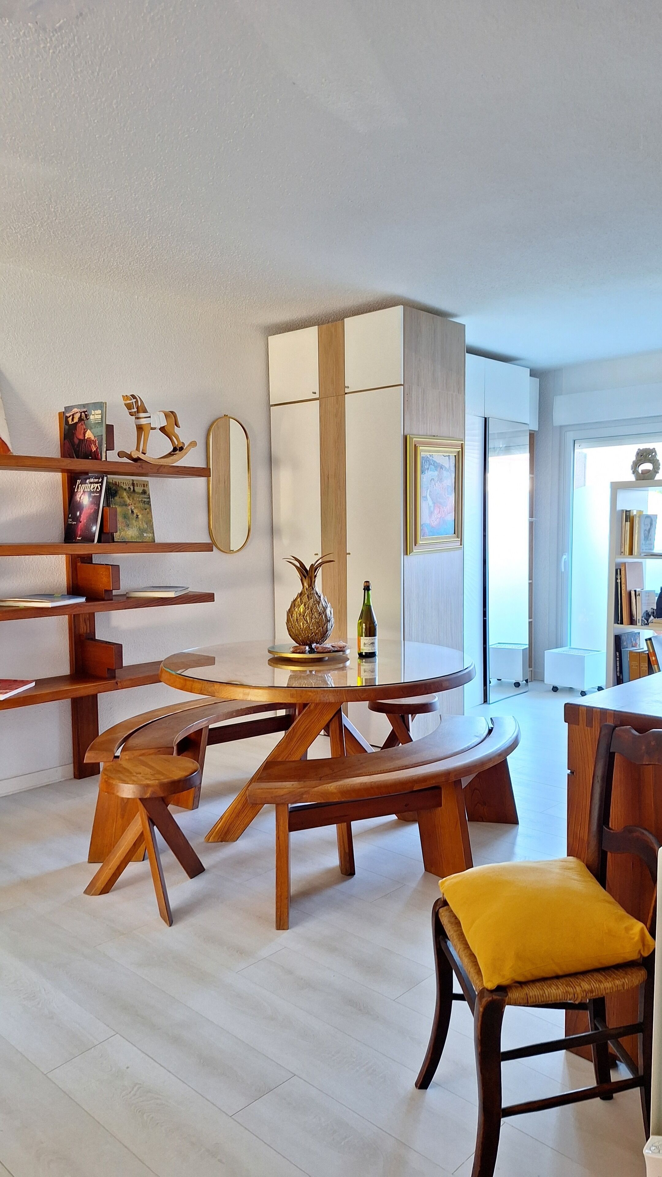 Un espace repas moderne avec des meubles en bois, une table ronde et un centre de table décoré d’un ananas.