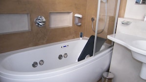 Un baño moderno con una bañera independiente, un cabezal de ducha de mano, un inodoro y un lavamanos.