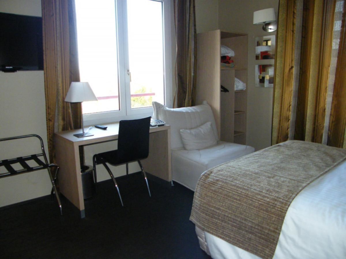 Una habitación de hotel con cama, escritorio, silla y armario.