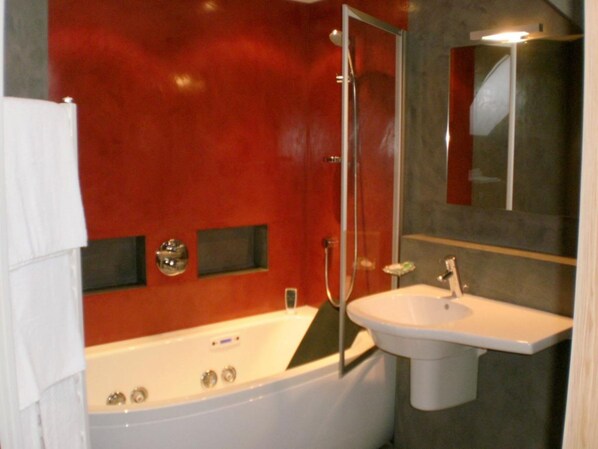 A bathroom with a white bathtub, a sink, and a glass-enclosed shower. - Hotel Saint Pierre (Vire-Normandie)