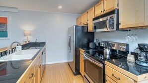 A modern kitchen with wooden cabinets, stainless steel appliances, a black countertop, and a built-in oven. - Centrally Located Condo | Walk to Gondola, Lift 8, Dining & River Trail (Telluride)