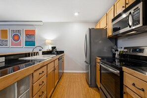Une cuisine moderne avec des meubles en bois, un réfrigérateur en acier inoxydable, un four à micro-ondes et une cuisinière.