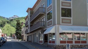 A multi-story building with balconies, a storefront, and a mountain backdrop. - Centrally Located Condo | Walk to Gondola, Lift 8, Dining & River Trail (Telluride)