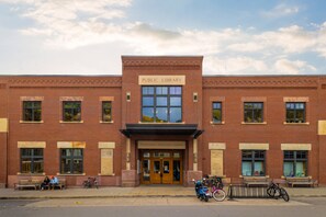 Une bibliothèque publique à la façade en briques, dotée de grandes fenêtres et d’une enseigne indiquant « Bibliothèque publique ».