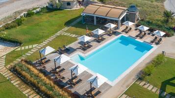 Relax by the pool surrounded by sun loungers and umbrellas with a view of the adjacent beach.