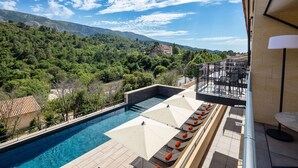 A poolside area with lounge chairs and umbrellas, overlooking a mountainous landscape. - Hotel Sainte Victoire (Vauvenargues)