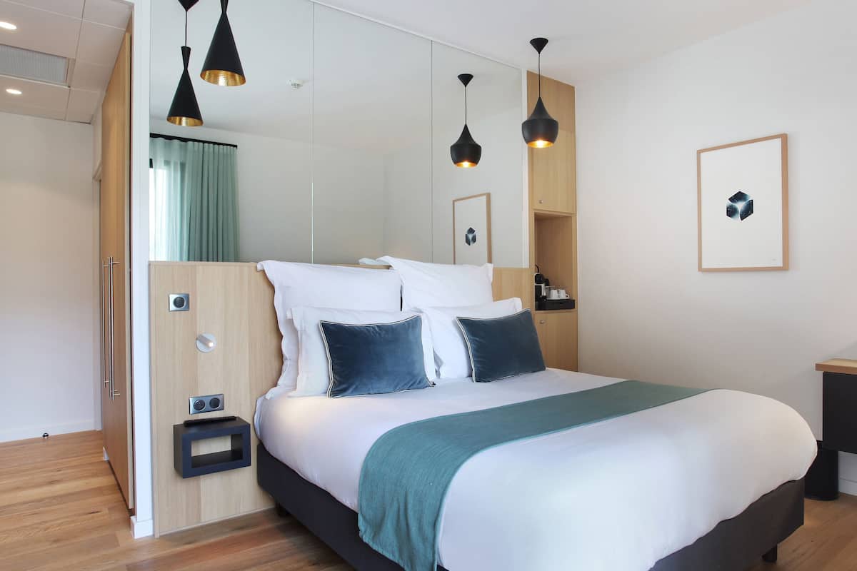 Una habitación de hotel moderna con una cama grande, mesitas de noche, un escritorio y un armario.