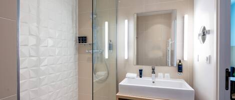 Een moderne badkamer met een douchecabine van glas, een wit wastafelmeubel met spiegel en een houten opbergkast.