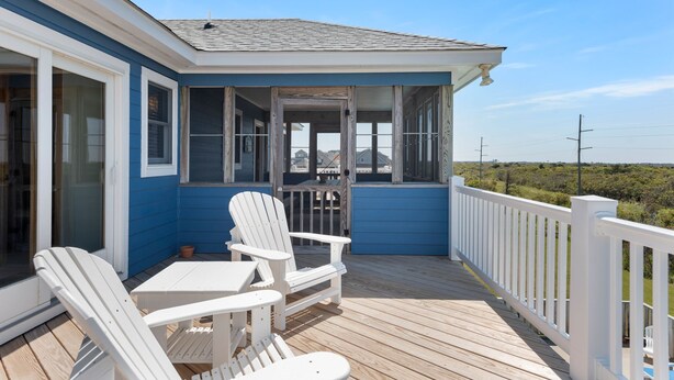 A covered deck with white Adirondack chairs and a table, overlooking a scenic landscape. - Wise Choice: Semi-oceanfront | Private Pool | Spa (Nags Head)